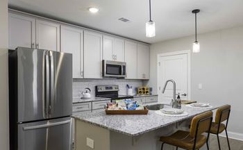 A modern kitchen with a stainless steel refrigerator and a granite countertop.