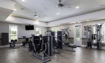 A spacious gym with a variety of equipment and a flat screen TV mounted on the wall.