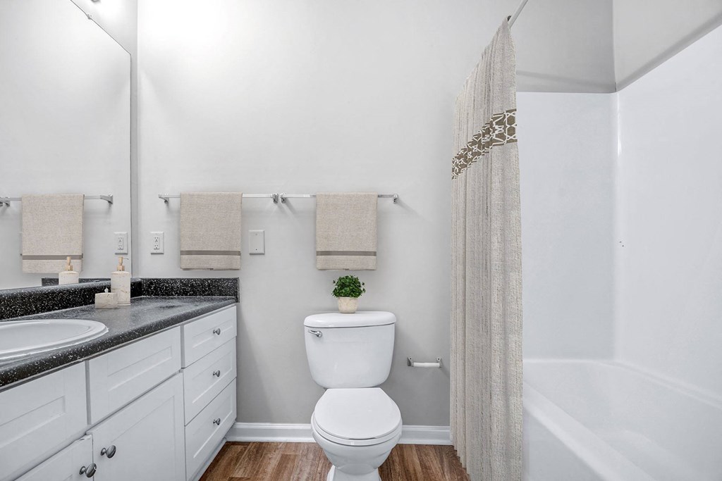 A white toilet in a bathroom with a white shower curtain.