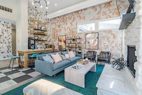 A living room with a grey couch and a white fireplace.