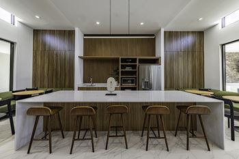 A modern kitchen with a long island and stools.