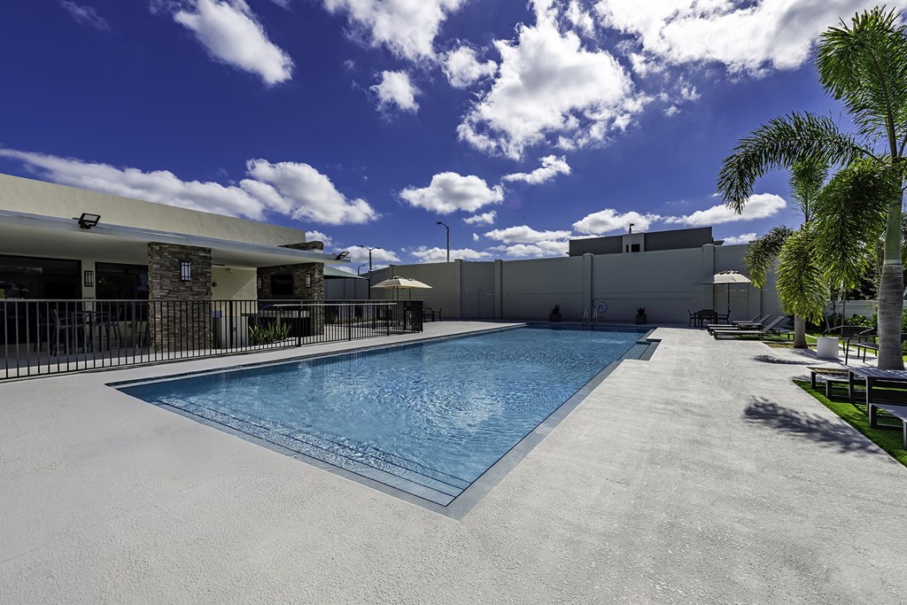 A large outdoor swimming pool with a concrete floor and a concrete wall on the right side.