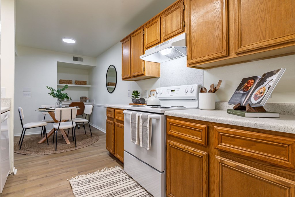 an open kitchen with wooden cabinets and a dining room with a table and chairs