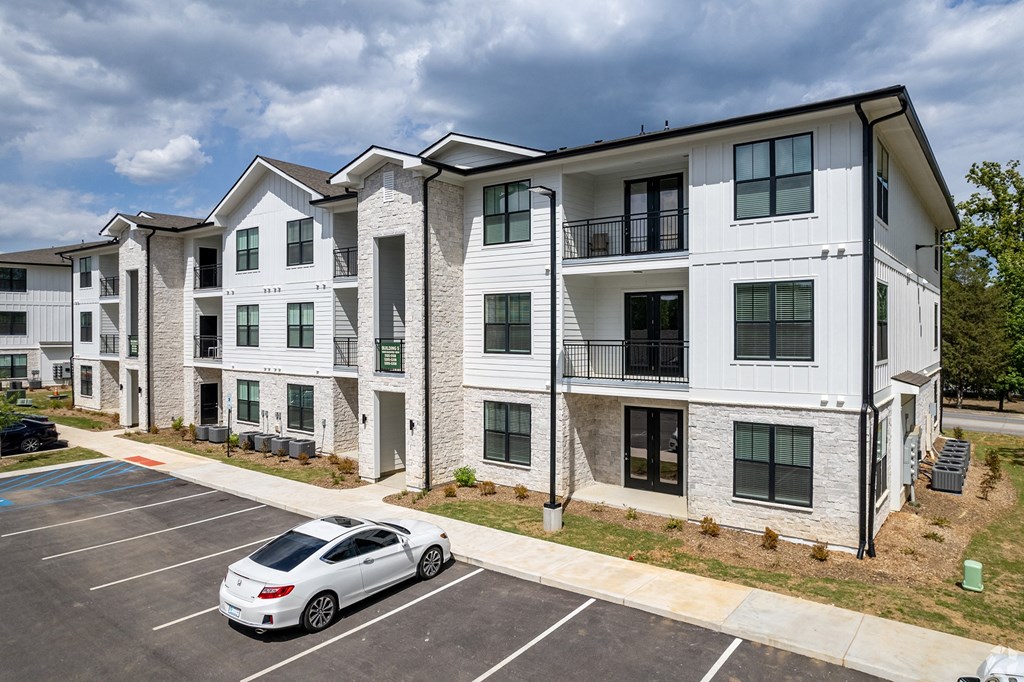 an apartment building with a white car parked in a parking lot