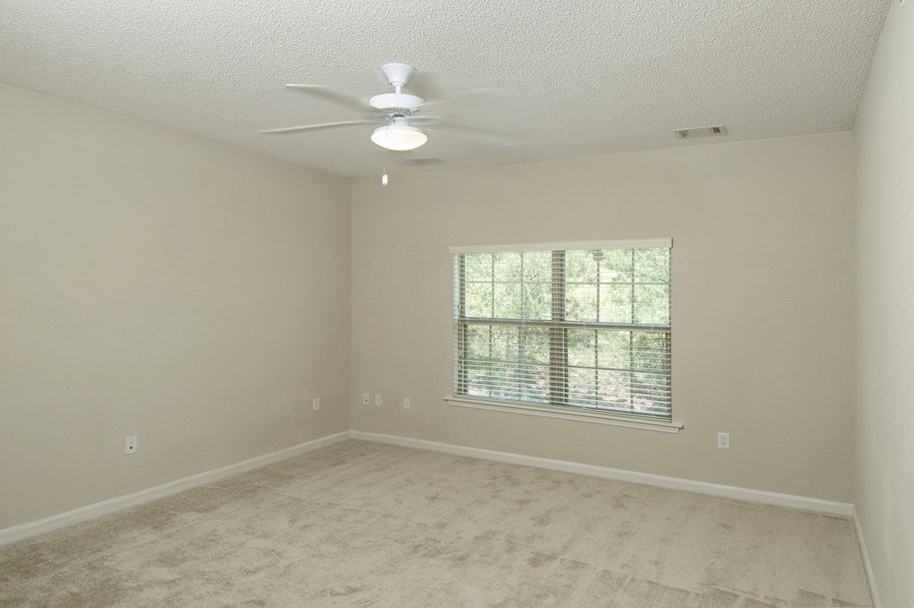 an empty living room with a ceiling fan and a window