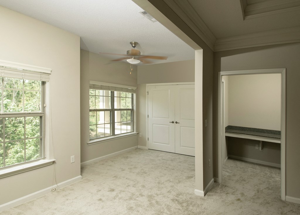 an empty living room with a ceiling fan and a closet