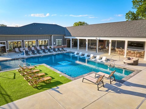 A large outdoor swimming pool with lounge chairs and a building in the background.