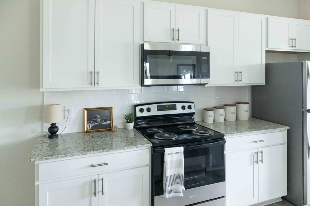 a kitchen with white cabinets and a stove and a microwave