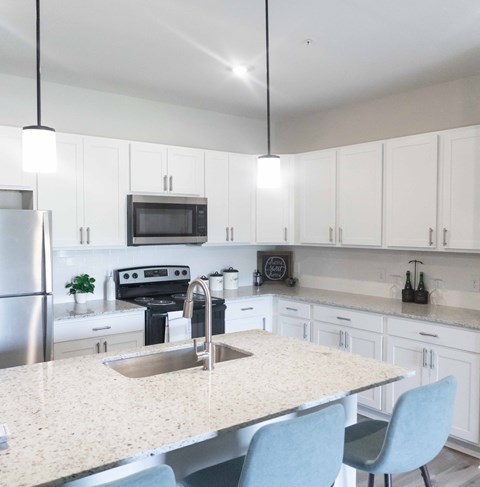 a kitchen with white cabinets and a marble counter top