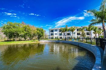 a pond in front of a building with palm trees at Altis Grand Suncoast, Florida