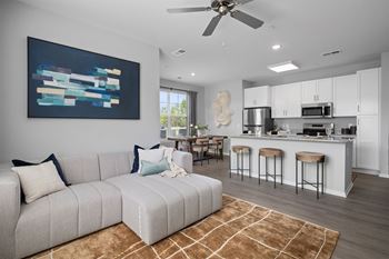 A modern living room with a grey sofa and a painting on the wall.