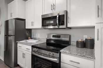 A black refrigerator and oven in a kitchen with white cabinets.