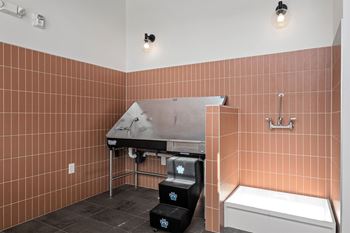 A bathroom with a brown tiled wall and a white bathtub.