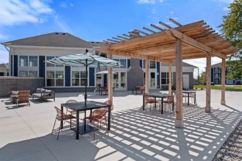 A patio with a table and chairs under a wooden pergola.