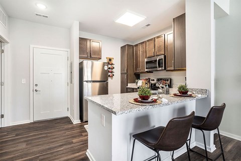 A kitchen with brown chairs and a white counter.