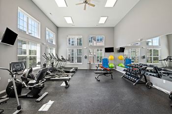 A spacious gym with a variety of cardio equipment and windows.