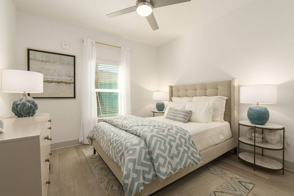 A bedroom with a large bed and a ceiling fan.