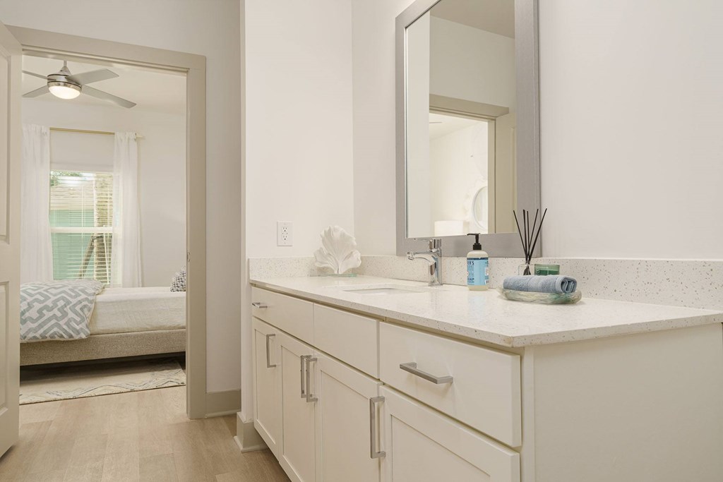 A bathroom with a white counter and a mirror.