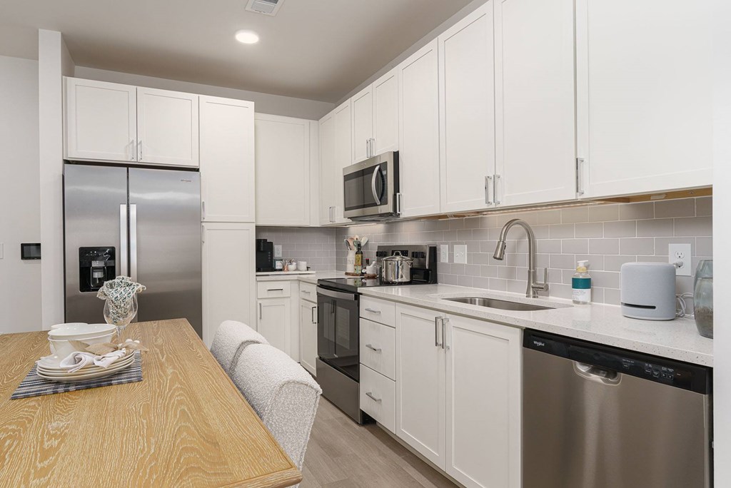 A modern kitchen with a wooden table and stainless steel appliances.
