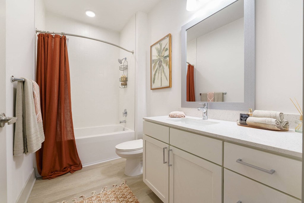 A bathroom with a white toilet, a white sink, and a brown shower curtain.