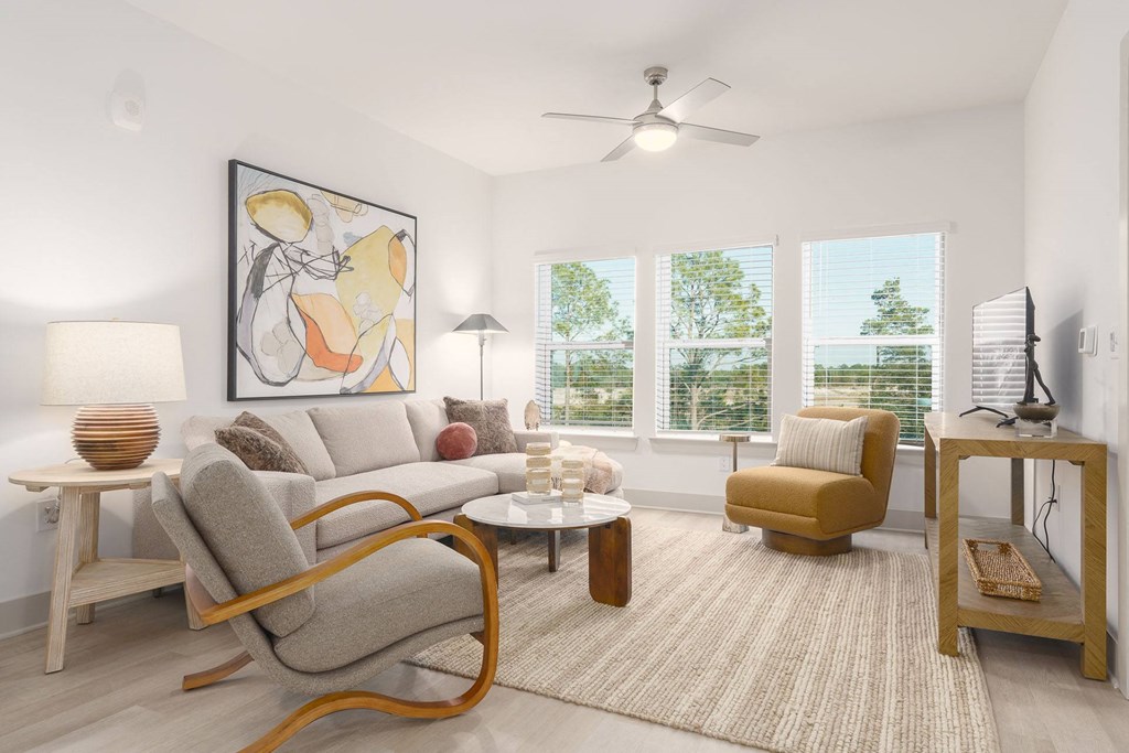 A living room with a grey couch, a yellow chair, a wooden table, and a painting on the wall.