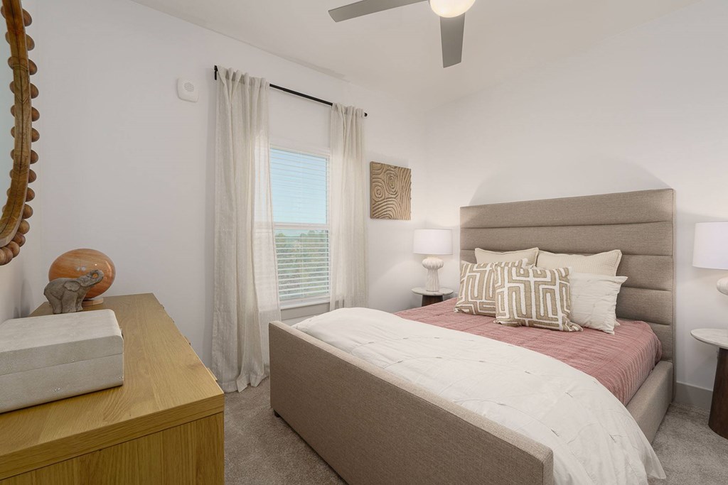A bedroom with a large bed and a wooden dresser.