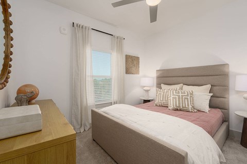 A bedroom with a large bed and a wooden dresser.