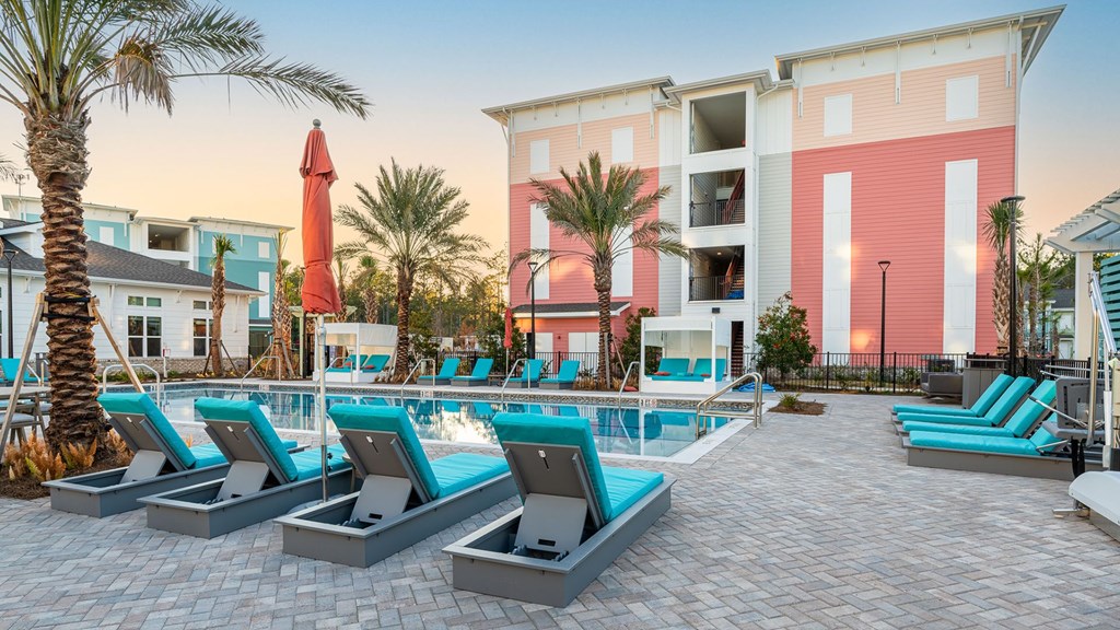 A pool area with lounge chairs and a palm tree.