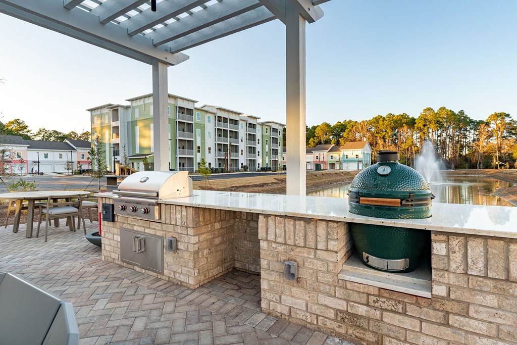 A BBQ grill is on a patio with a building in the background.