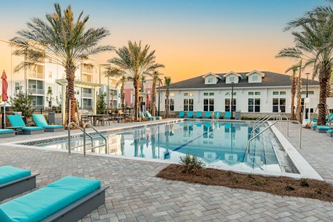 A pool surrounded by palm trees and lounge chairs.