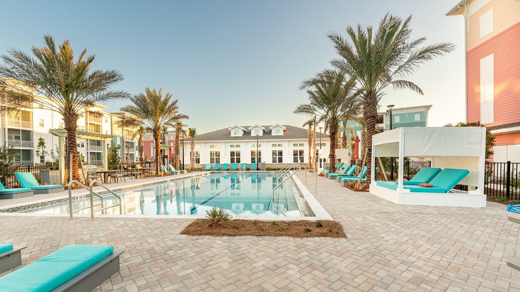 A pool surrounded by palm trees and lounge chairs.