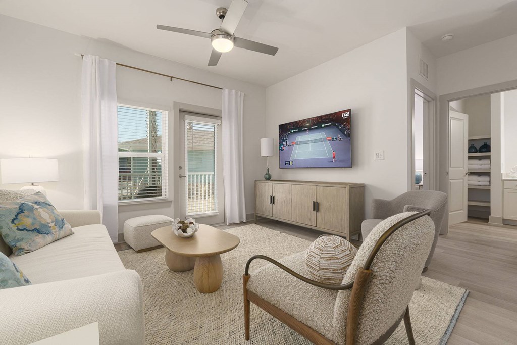 A living room with a white couch, a chair, and a television.