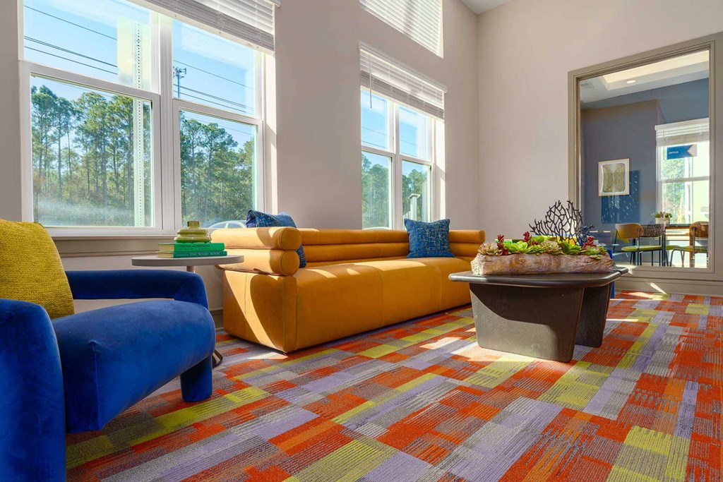 A brightly colored carpeted room with a yellow sofa and blue chairs.