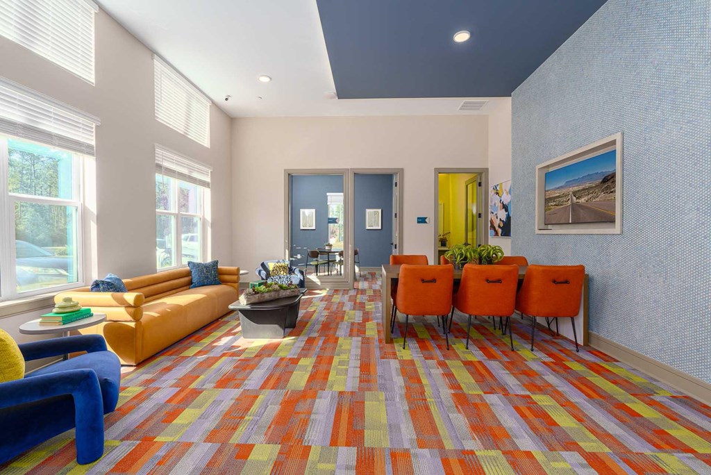 A brightly colored carpeted hallway with orange chairs and a yellow couch.