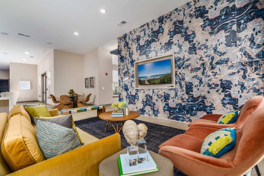 A living room with a yellow sofa, a brown armchair, and a blue and white patterned wallpaper.