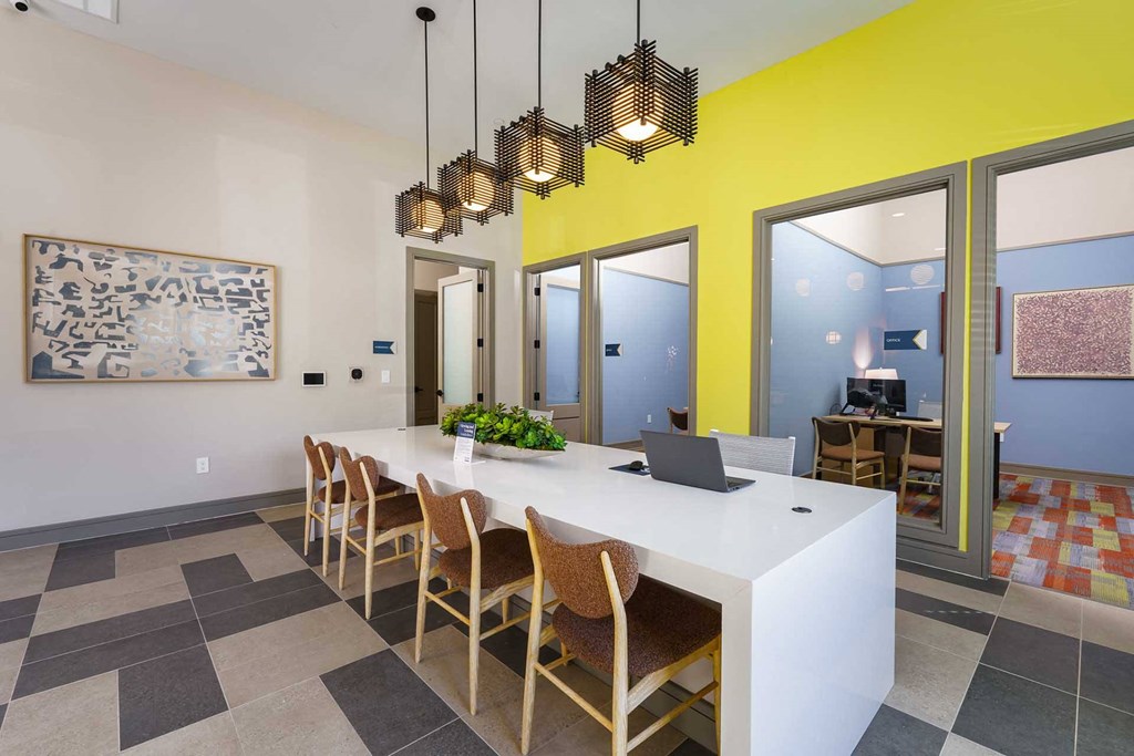 A long white table with chairs and a plant on it.