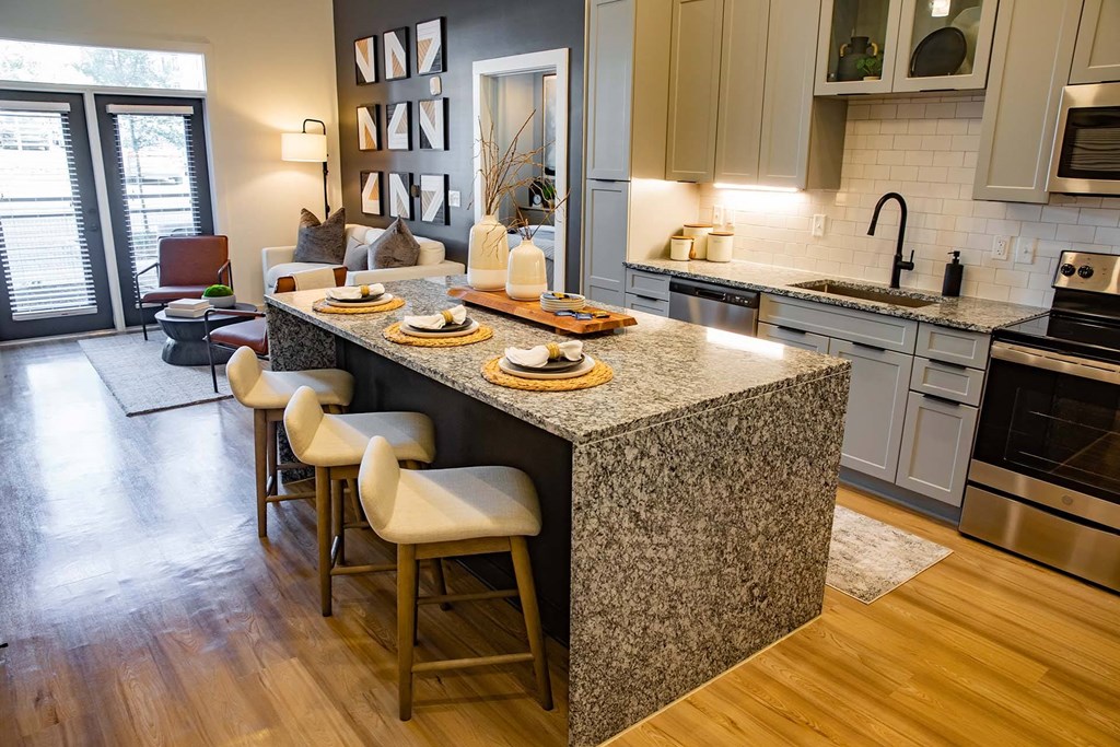 a kitchen with a large island and a living room in the background