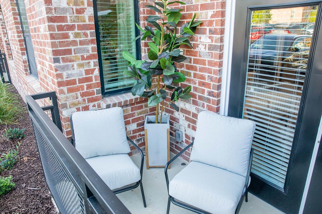 a balcony with two chairs and a plant
