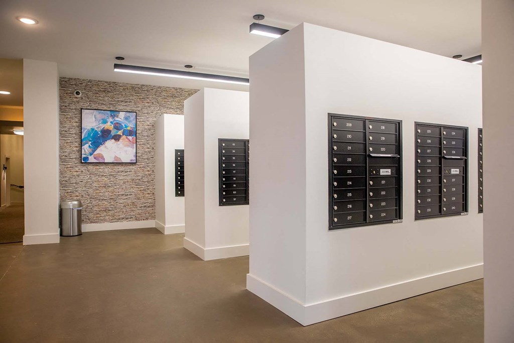 a wall of mailboxes in a room with a painting on the wall