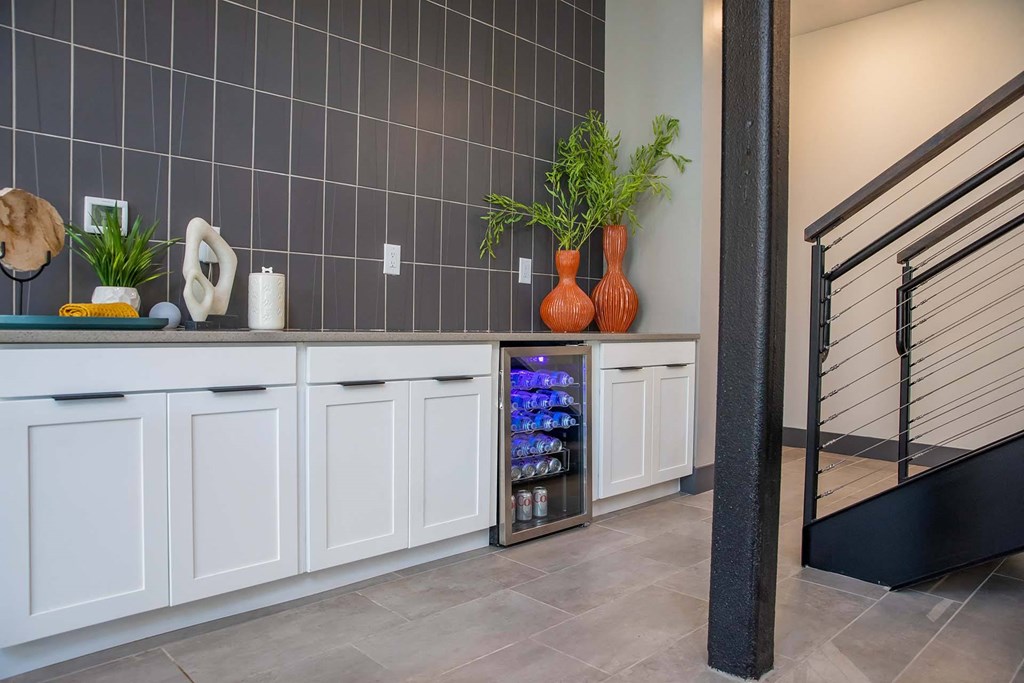 a kitchen with white cabinets and a black and white tiled wall