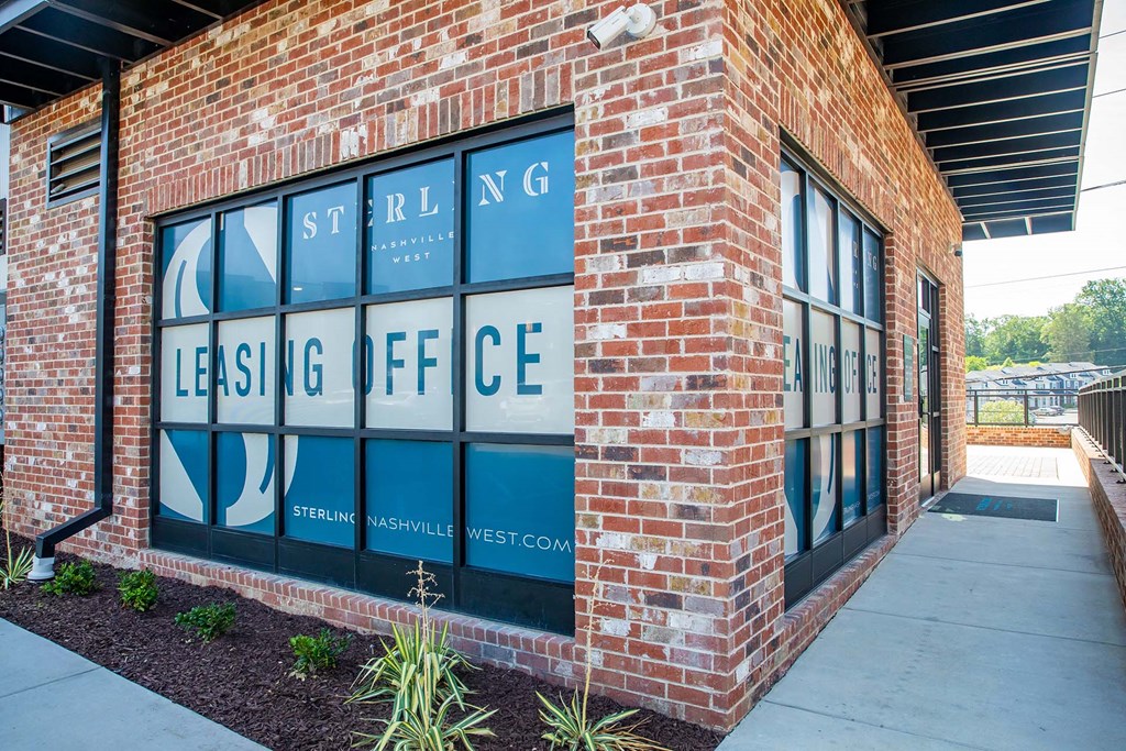 a brick building with a sign in the window that reads leasing office