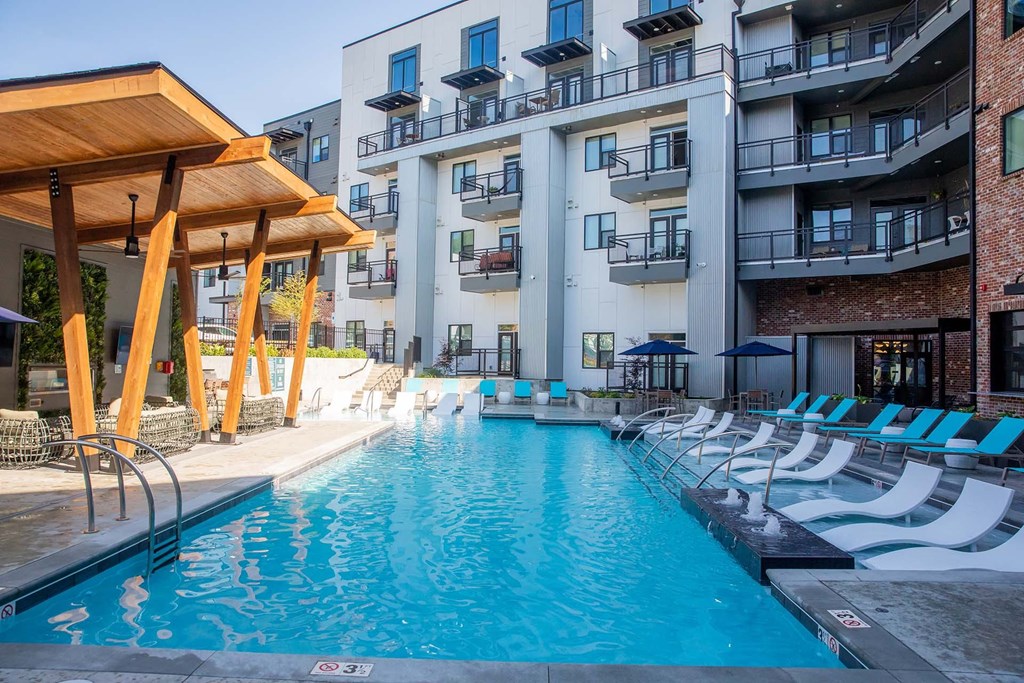 an outdoor pool with chaise lounge chairs and a building in the background
