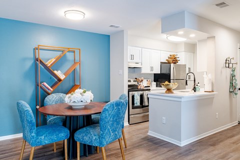 A dining room with a round table and blue chairs.
