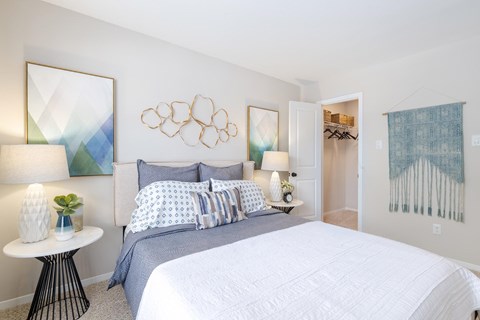 A bedroom with a large bed and a painting on the wall.