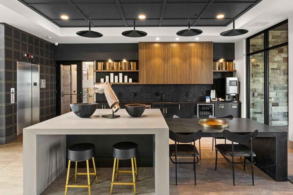 a kitchen with a large island with black chairs and a counter