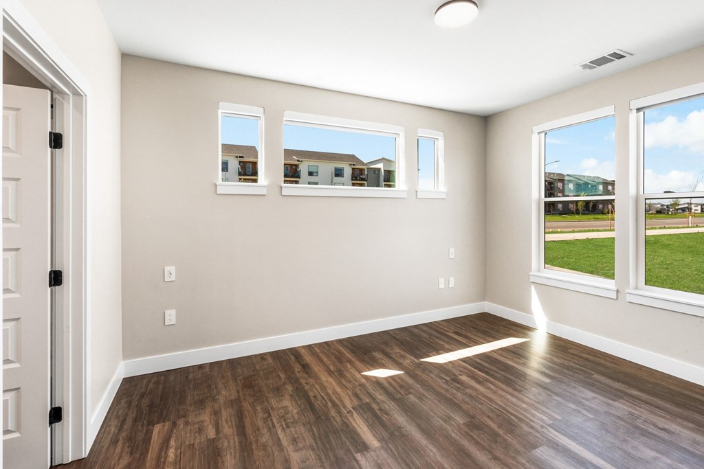 an empty living room with a wood floor and windows