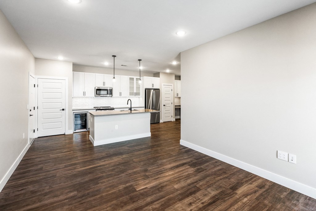 an empty living room and kitchen with white walls and wood floors