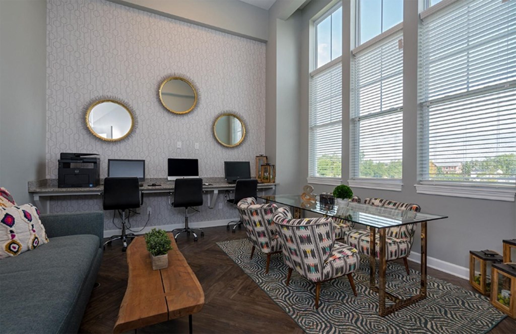 A living room with a grey couch, a glass table, and a wall with three round mirrors.