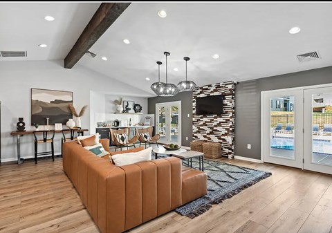 A living room with a brown sofa and a TV mounted on the wall.