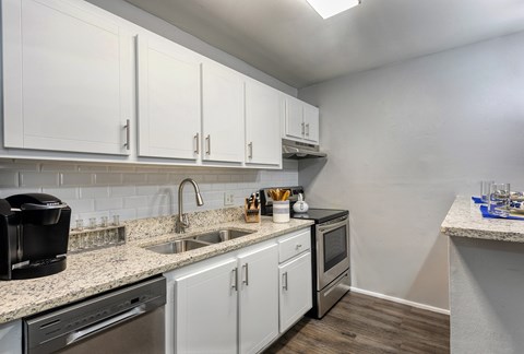 A kitchen with white cabinets and a black coffee maker.